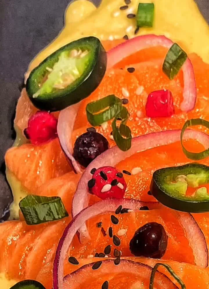 Primer pla del tiradito de salmó d’Omnívor amb jalapeño i ceba